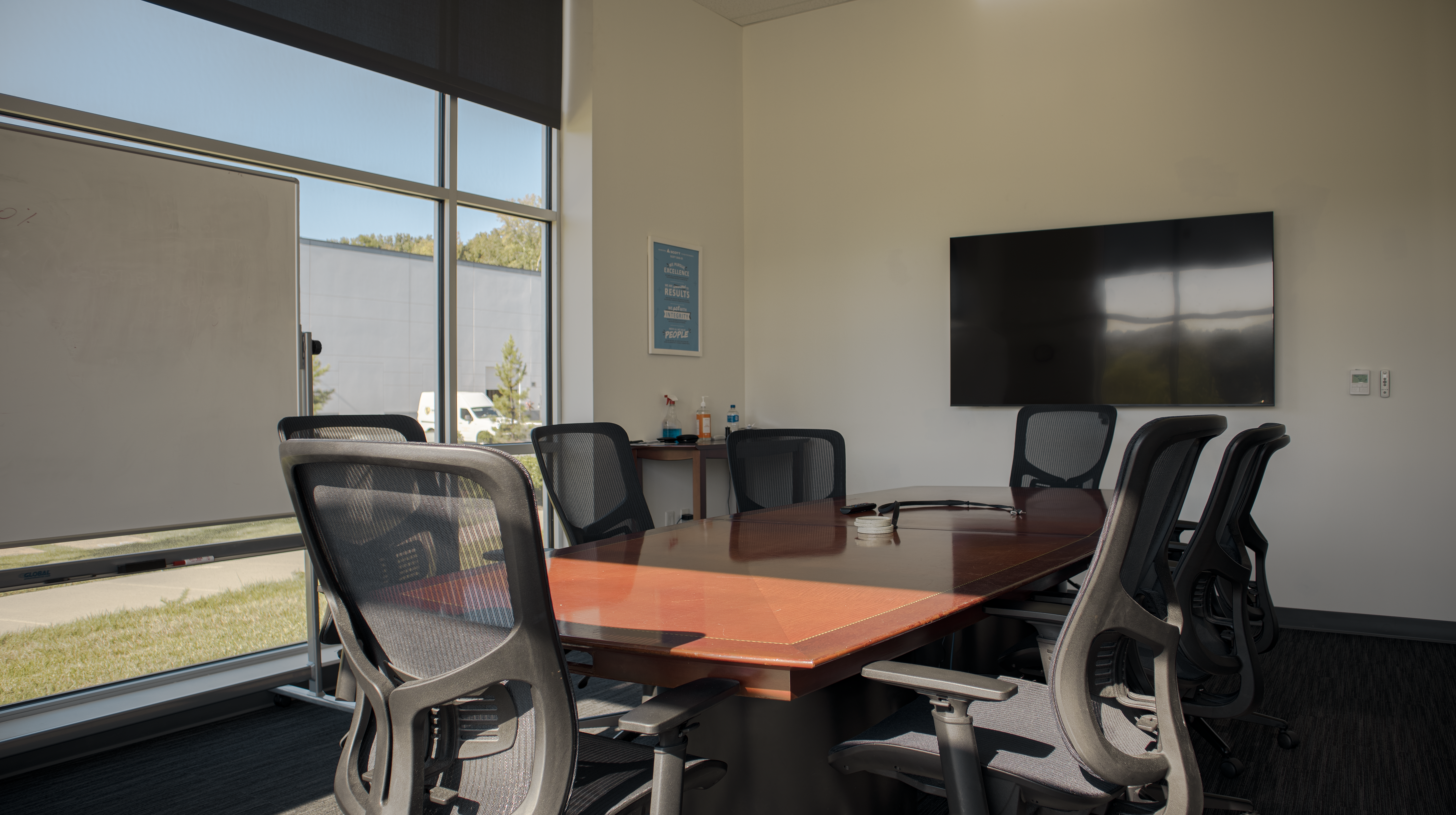 A naturally lit, beige-walled conference room during a clear summer day in the afternoon.